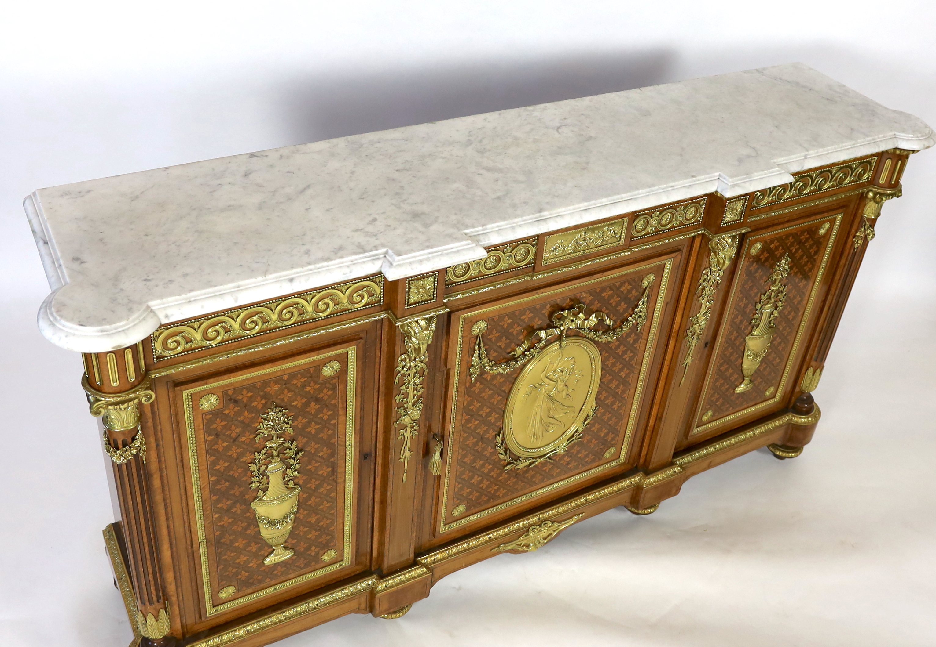 A Louis XVI style amboyna, tulipwood and harewood marquetry side cabinet, in the manner of Adam Weisweiler (1744-1820), 210cm wide, 48cm deep, 115cm high, Please note this lot attracts an additional import tax of 5% on t